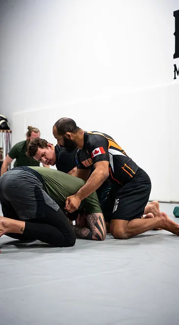 Coaches and students grappling during an evening training session at Mission BJJ
